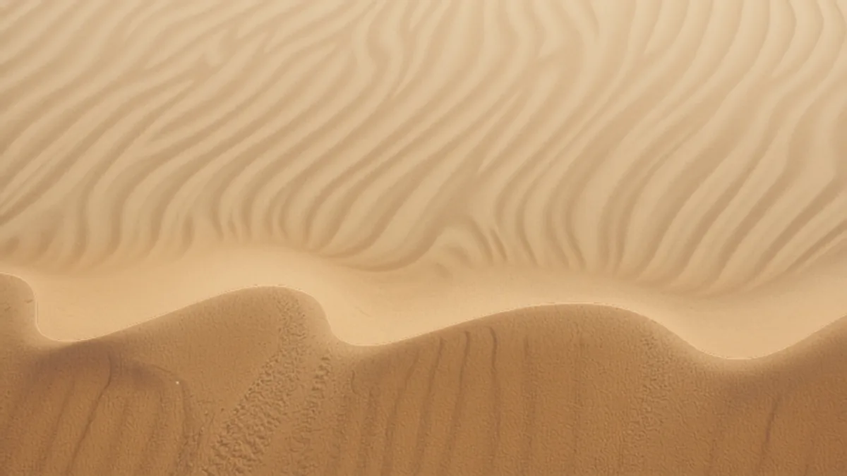Abstrakte Nahaufnahme von Sanddünen in warmen Cream- und Brauntönen